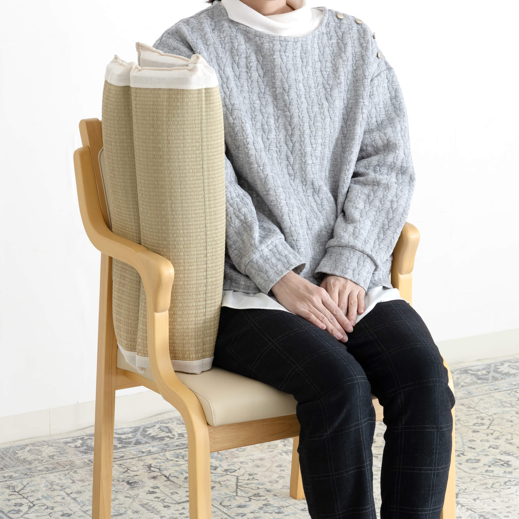 肘掛と身体の間にクッションを挟む座り方